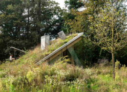W sercu holenderskiego Parku Narodowego De Hoge Veluwe, na terenie dawnej bazy wojskowej, powstał niezwykły dom wakacyjny autorstwa pracowni JCR Architects. Projekt, o powierzchni zaledwie 43 m², wpisuje się w ideę „architektury niewidzialnej” – znaczna część budynku została schowana pod powierzchnią gruntu, a to, co pozostaje widoczne, niemal całkowicie stapia się z otaczającą przyrodą. 